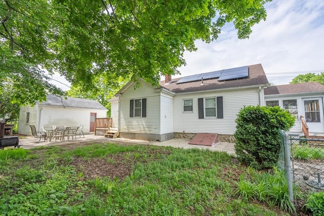7 Prospect Ave, Dudley, MA 01571 - back of property featuring a patio area, roof mounted solar panels, fence, and a chimney