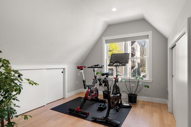exercise area featuring vaulted ceiling, wood finished floors, and baseboards