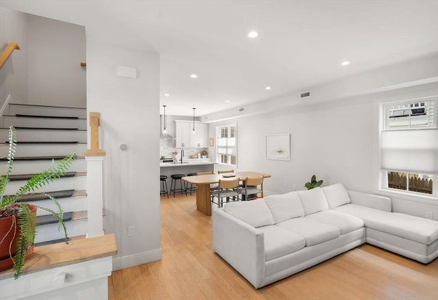 living area with light wood-style flooring, stairs, and recessed lighting
