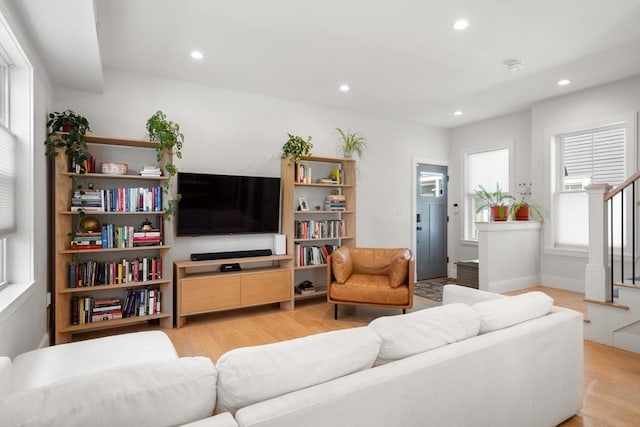 living area with light wood-style flooring, recessed lighting, and stairs