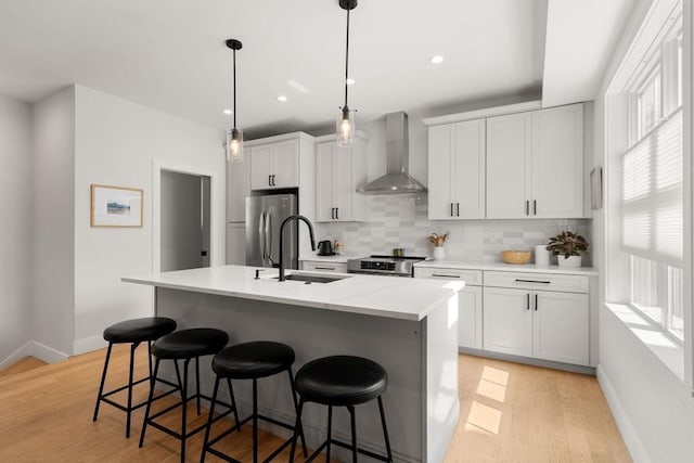 kitchen with wall chimney exhaust hood, a sink, stainless steel appliances, plenty of natural light, and recessed lighting