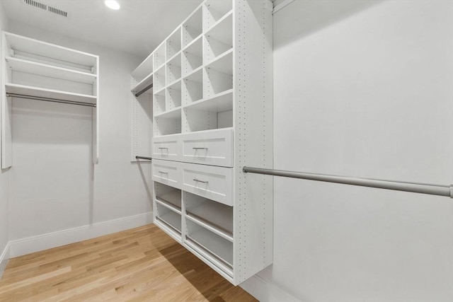 walk in closet with light hardwood / wood-style floors