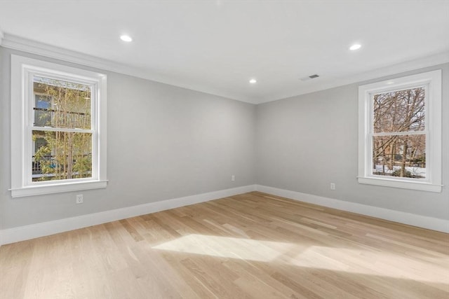 empty room featuring light wood-type flooring, plenty of natural light, and ornamental molding