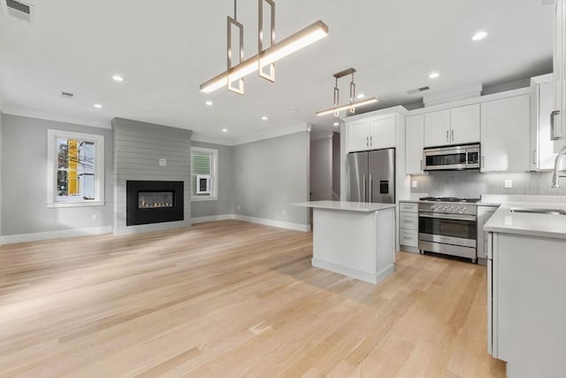 kitchen featuring decorative light fixtures, a center island, white cabinetry, and stainless steel appliances