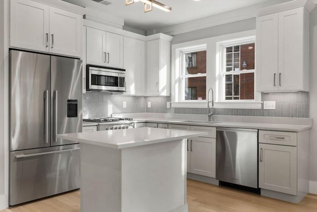 kitchen featuring white cabinets, a kitchen island, stainless steel appliances, and a sink