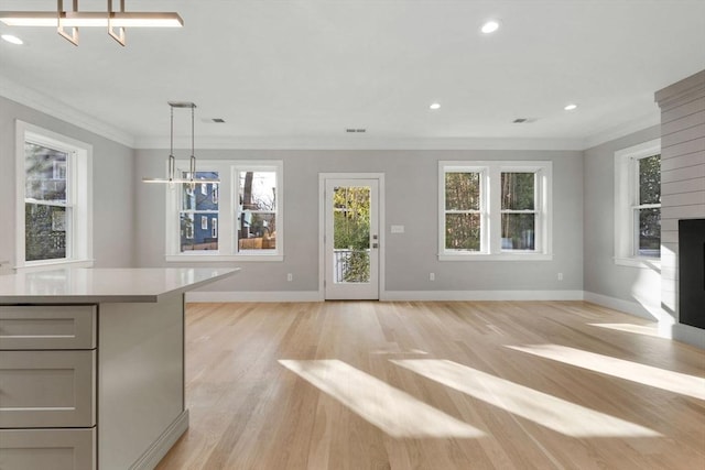 unfurnished living room featuring crown molding, a chandelier, and light wood-type flooring