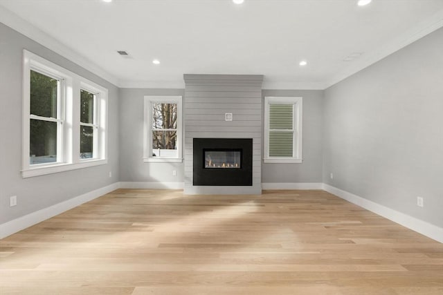 unfurnished living room featuring light wood-type flooring, a large fireplace, and ornamental molding