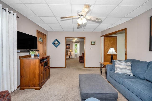 living area with a paneled ceiling, light carpet, ceiling fan, and baseboards
