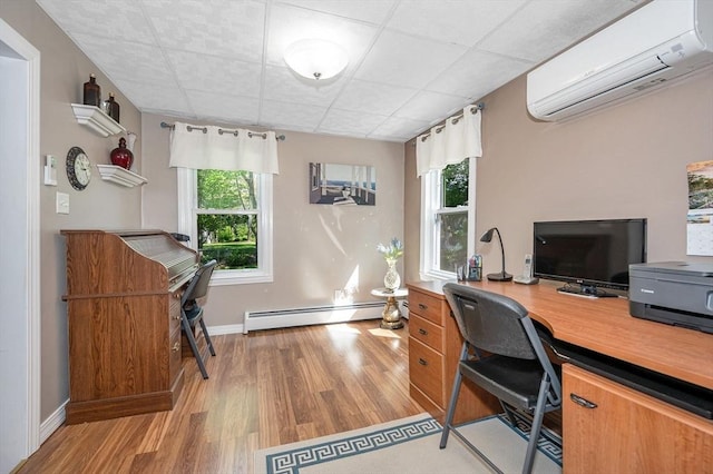 home office with a wall mounted AC, baseboard heating, wood finished floors, baseboards, and a drop ceiling