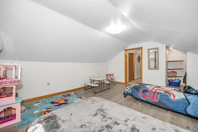 bedroom featuring wood finished floors, vaulted ceiling, and baseboards
