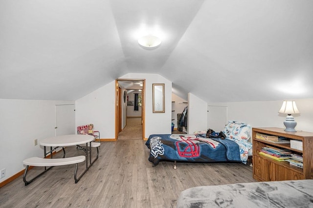 bedroom with wood finished floors, vaulted ceiling, and baseboards
