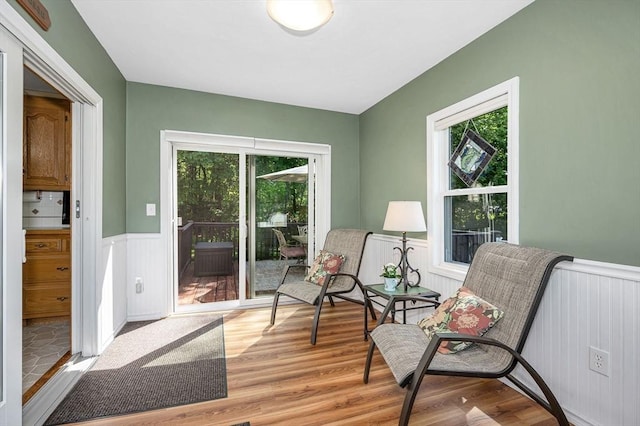 living area with a wainscoted wall, light wood-style flooring, and plenty of natural light