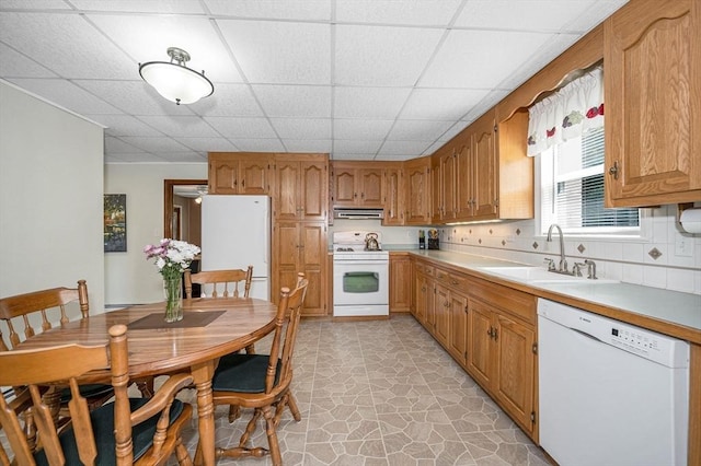 kitchen with white appliances, a sink, extractor fan, a drop ceiling, and light countertops