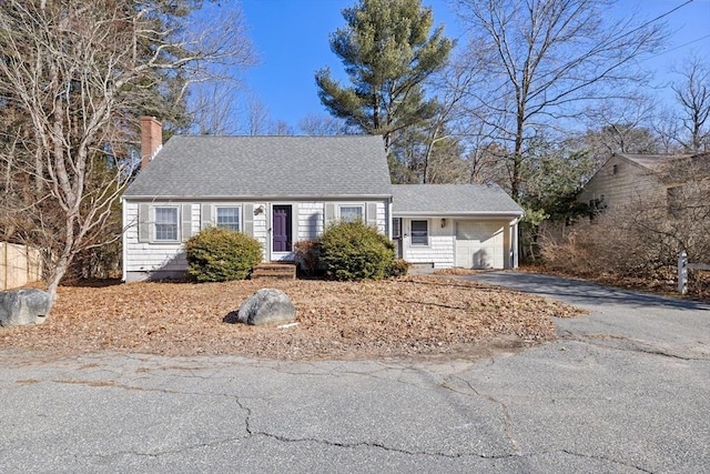 cape cod house with aphalt driveway, roof with shingles, a chimney, and an attached garage