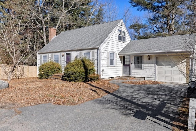 new england style home with a garage, a chimney, aphalt driveway, roof with shingles, and fence