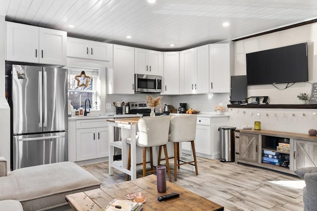 kitchen featuring sink, light hardwood / wood-style flooring, a breakfast bar, white cabinetry, and stainless steel appliances