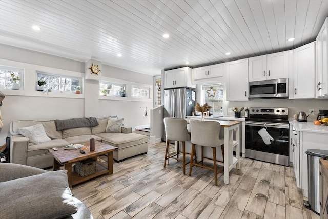 kitchen featuring wood ceiling, a breakfast bar, stainless steel appliances, light hardwood / wood-style floors, and white cabinets