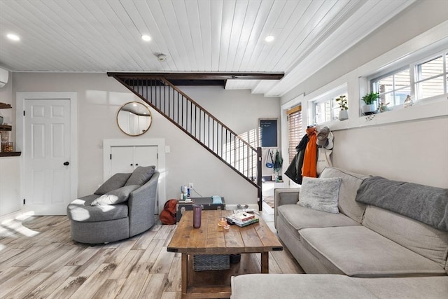 living room featuring beamed ceiling, a wall mounted AC, light hardwood / wood-style flooring, and wooden ceiling