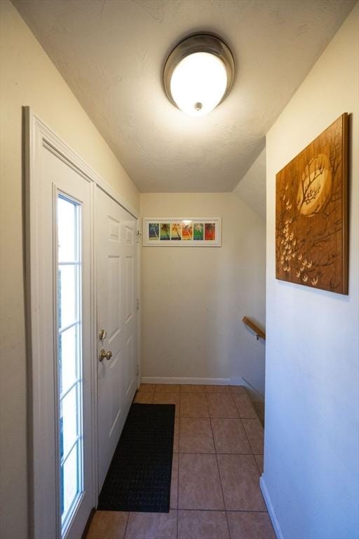 doorway featuring tile patterned flooring and lofted ceiling