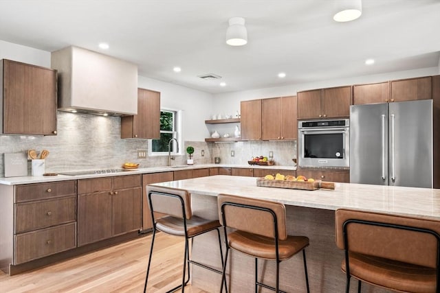 1 Archer St, Swampscott, MA 01907 - kitchen featuring stainless steel appliances, open shelves, light wood-type flooring, a kitchen breakfast bar, and custom exhaust hood
