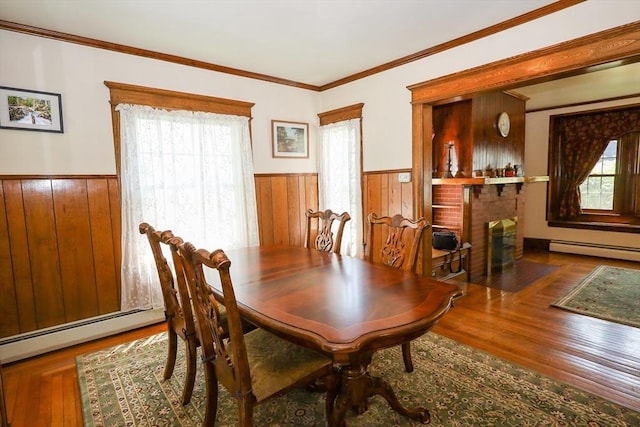88 Biltmore St, Springfield, MA 01108 - dining area featuring baseboard heating, wainscoting, wood finished floors, wood walls, and a fireplace