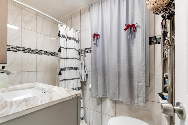 bathroom with walk in shower, vanity, toilet, and tile walls