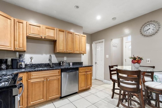 kitchen with light tile patterned floors, appliances with stainless steel finishes, sink, and dark stone countertops