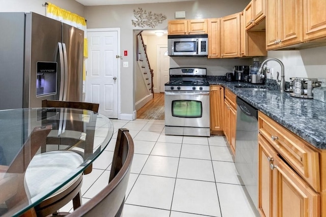 kitchen featuring light tile patterned floors, appliances with stainless steel finishes, sink, and dark stone countertops