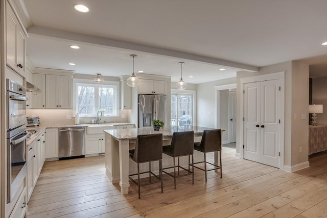 41 Pleasant St, Holliston, MA 01746 - kitchen featuring stainless steel appliances, a sink, a center island, light wood finished floors, and a kitchen bar