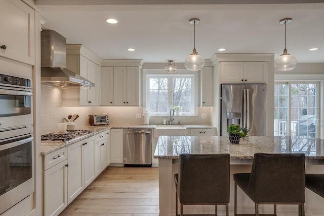 41 Pleasant St, Holliston, MA 01746 - kitchen with appliances with stainless steel finishes, wall chimney exhaust hood, a kitchen breakfast bar, decorative backsplash, and recessed lighting