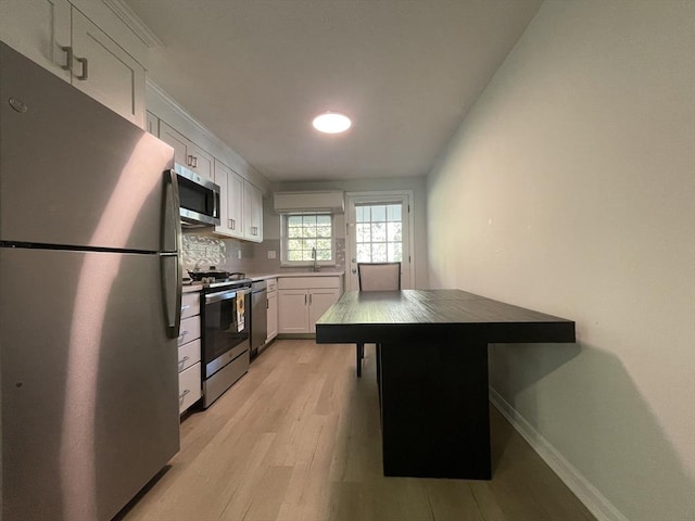 kitchen with sink, tasteful backsplash, appliances with stainless steel finishes, light hardwood / wood-style floors, and white cabinets