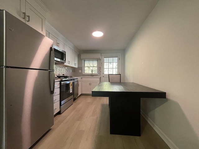 kitchen with sink, appliances with stainless steel finishes, tasteful backsplash, light hardwood / wood-style floors, and white cabinets