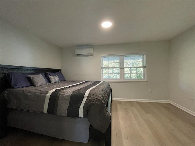 bedroom with a wall mounted air conditioner and light hardwood / wood-style flooring