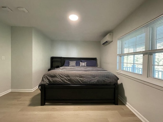 bedroom with an AC wall unit and light wood-type flooring