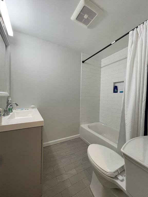 full bathroom featuring shower / bathtub combination with curtain, vanity, and toilet