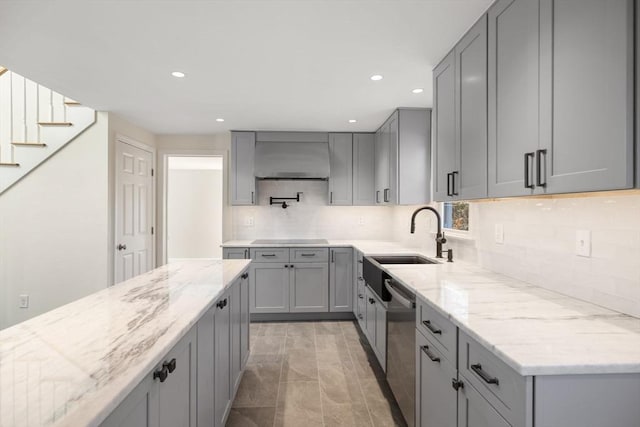 kitchen with gray cabinets, light stone countertops, and wall chimney range hood