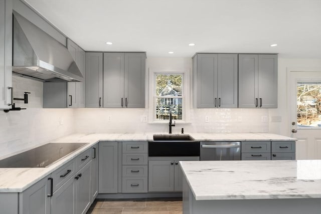 kitchen with black electric stovetop, gray cabinets, stainless steel dishwasher, and wall chimney exhaust hood