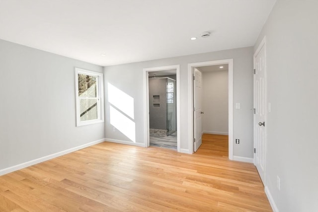 unfurnished bedroom featuring a spacious closet, light hardwood / wood-style flooring, and a closet