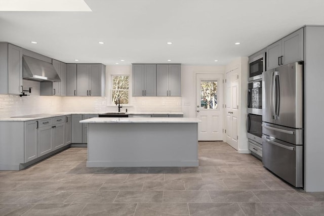 kitchen with sink, gray cabinets, stainless steel appliances, a kitchen island, and exhaust hood