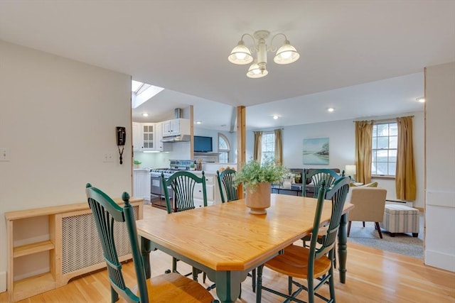 dining space with an inviting chandelier, a skylight, radiator, and light wood-type flooring