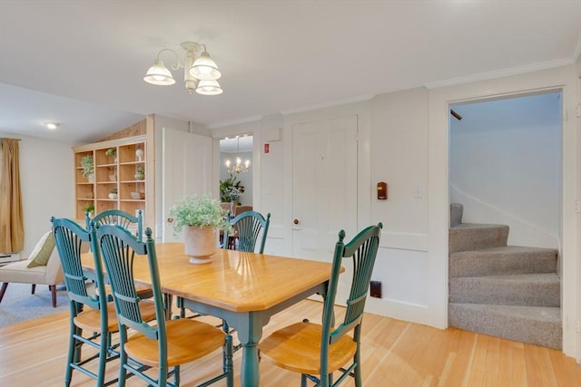 dining area with crown molding, lofted ceiling, a chandelier, and light hardwood / wood-style floors