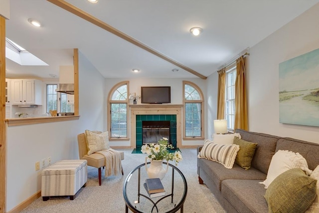 living room featuring a fireplace, vaulted ceiling with skylight, and light carpet