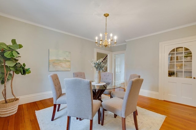 dining space with crown molding, a chandelier, and light hardwood / wood-style floors