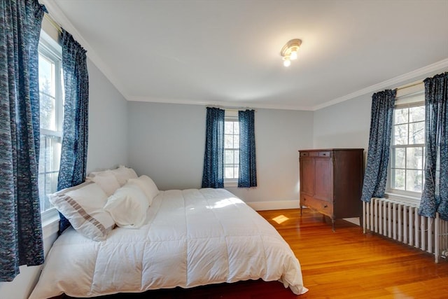 bedroom with hardwood / wood-style flooring, radiator heating unit, and crown molding