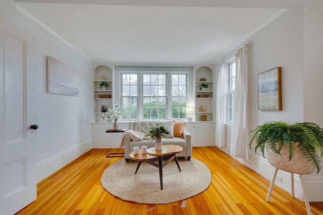 sitting room featuring crown molding, built in features, and hardwood / wood-style flooring