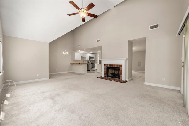 unfurnished living room featuring light colored carpet, baseboards, ceiling fan with notable chandelier, and high vaulted ceiling