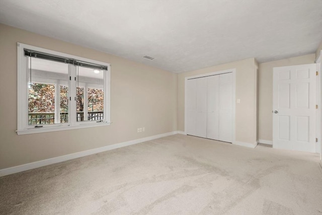 unfurnished bedroom with carpet floors, baseboards, a closet, and visible vents