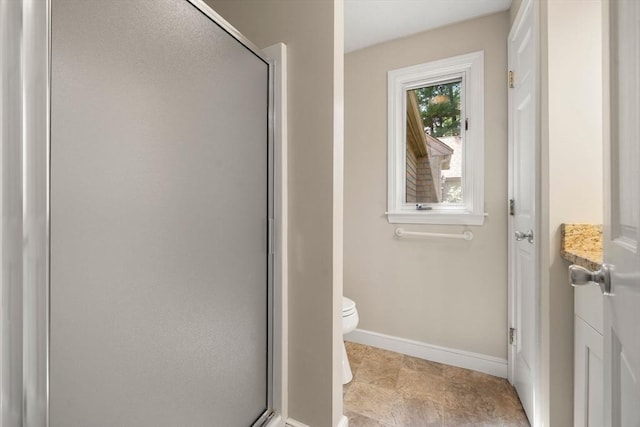 full bathroom featuring baseboards, a shower with shower door, and toilet