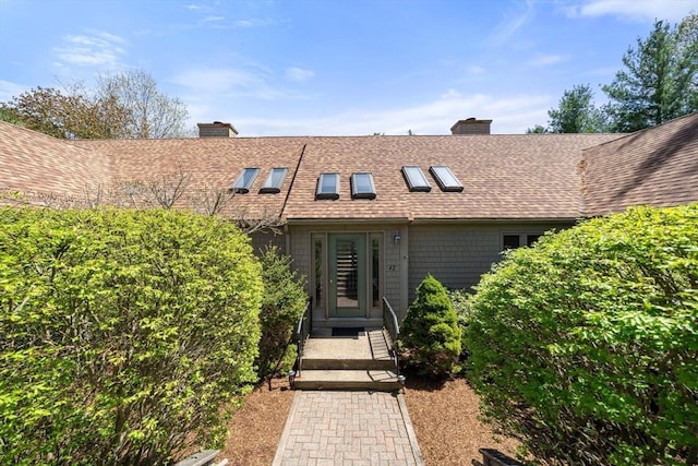 property entrance featuring roof with shingles and a chimney
