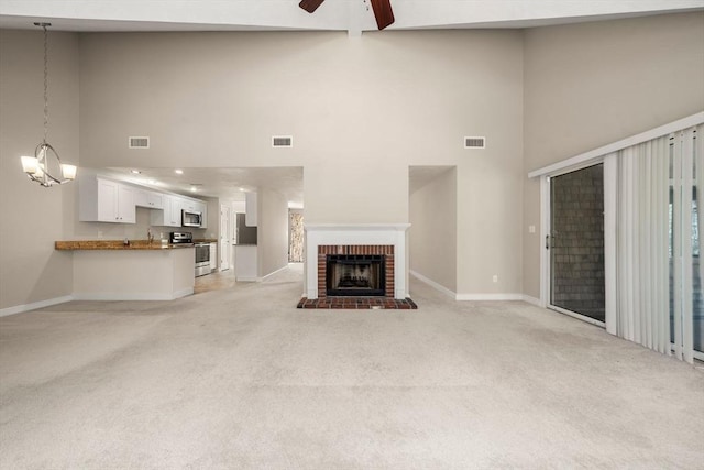 unfurnished living room with light carpet, a towering ceiling, baseboards, and visible vents
